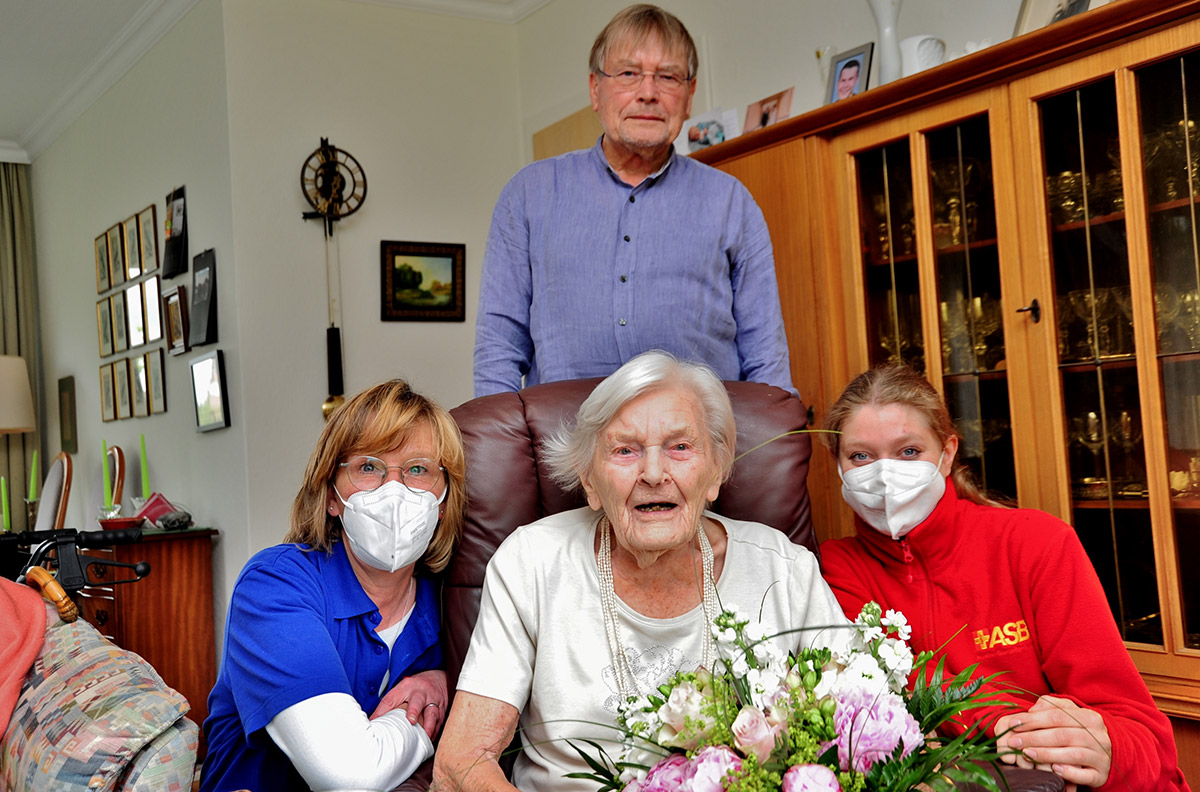 Tina Marks (li.) und Dominique Kolla-Werger (re.) vom ASB überraschen Anneliese Grund und ihren Sohn Uwe Grund mit einem Blumenstrauß